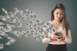 poor Asian woman holding purse having problem with money flying away, over spending concept