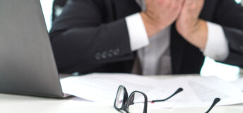 Stressed business man covering face with hands in office. Working over time or too much. Problem with failing business or confusion with crisis. Entrepreneur in bankruptcy.