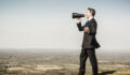 Picture of a businessman with loudhailer megaphone on hill.