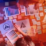 Marketing executives and graphic designers spread logo options and colour swatches over a table to decide on a rebrand