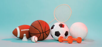 A pile of various sports equipment including a basketball, a shuttlecock and some weights